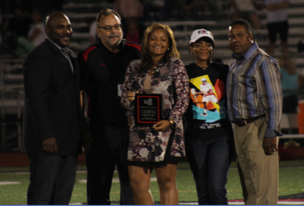 A group of people taking picture and a woman holding a award